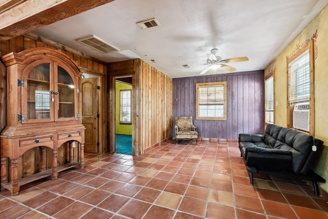 living room featuring dark tile floors, ceiling fan, and wooden walls