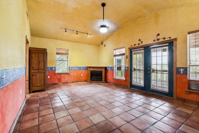 interior space featuring dark tile flooring, vaulted ceiling, a wealth of natural light, and track lighting