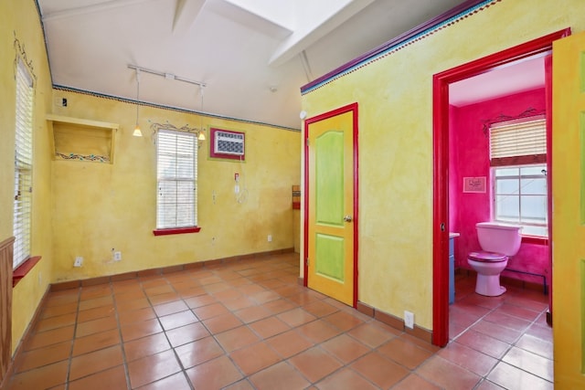 unfurnished room featuring dark tile floors, rail lighting, and a wealth of natural light