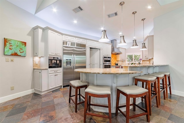 kitchen featuring tasteful backsplash, kitchen peninsula, wall chimney range hood, and stainless steel appliances