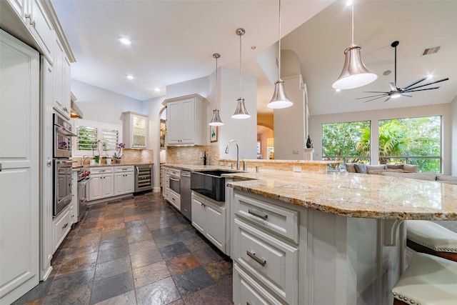 kitchen featuring backsplash, a kitchen bar, ceiling fan, and a healthy amount of sunlight