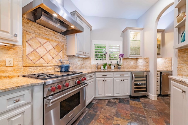 kitchen with appliances with stainless steel finishes, tasteful backsplash, beverage cooler, and wall chimney exhaust hood