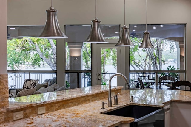 kitchen featuring hanging light fixtures, light stone counters, and sink