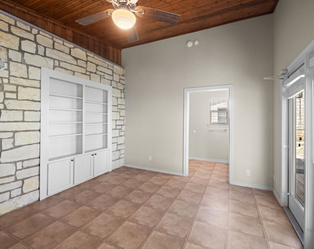 spare room featuring ceiling fan, built in shelves, wood ceiling, and light tile floors