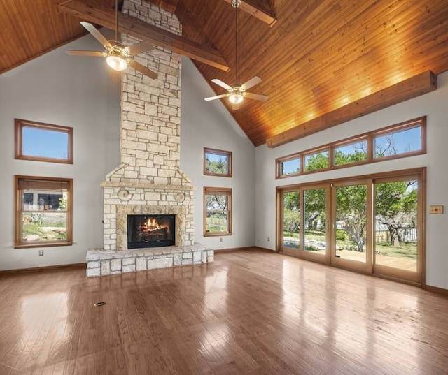 unfurnished living room featuring a stone fireplace, high vaulted ceiling, ceiling fan, and beamed ceiling