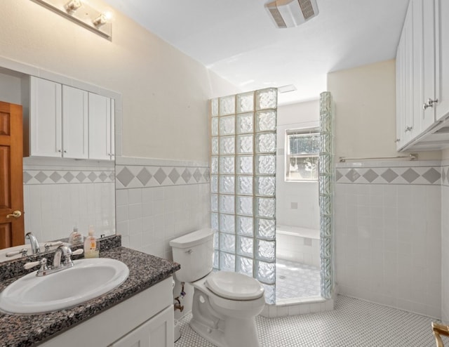 bathroom with tile walls, a shower, tile floors, large vanity, and toilet