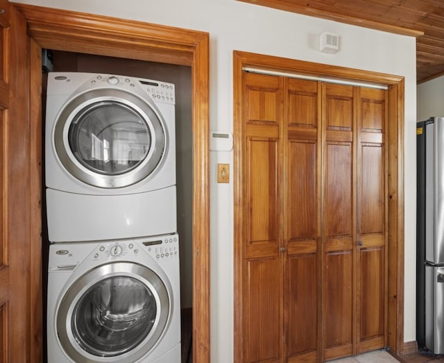 washroom with wood ceiling and stacked washer / dryer