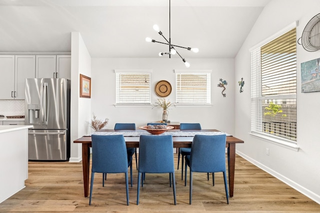 dining room featuring vaulted ceiling, a chandelier, and light hardwood / wood-style flooring