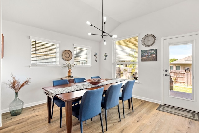 dining room with an inviting chandelier, light hardwood / wood-style flooring, a healthy amount of sunlight, and vaulted ceiling