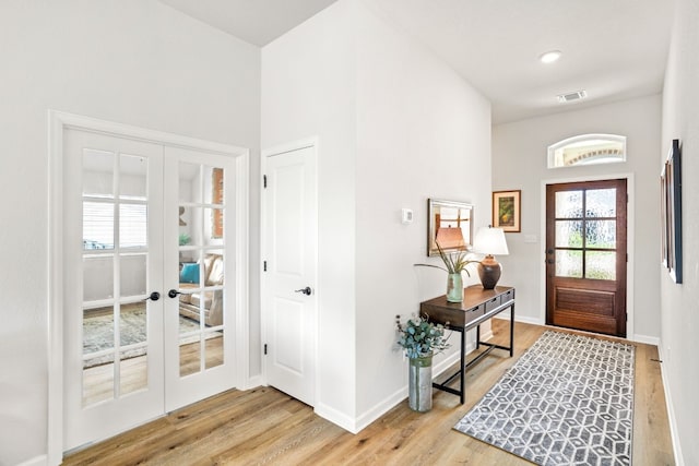 foyer entrance with light hardwood / wood-style floors, french doors, and a high ceiling