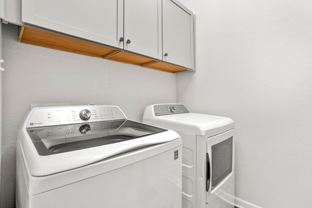 laundry area with washing machine and clothes dryer and cabinets