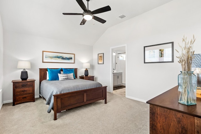 bedroom with ceiling fan, ensuite bathroom, light carpet, and vaulted ceiling