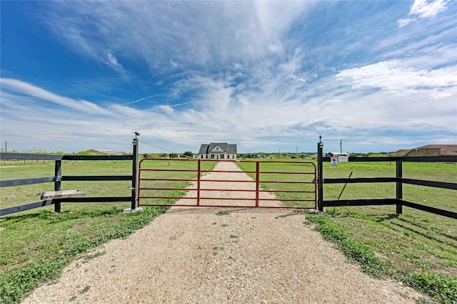 view of gate with a rural view and a lawn