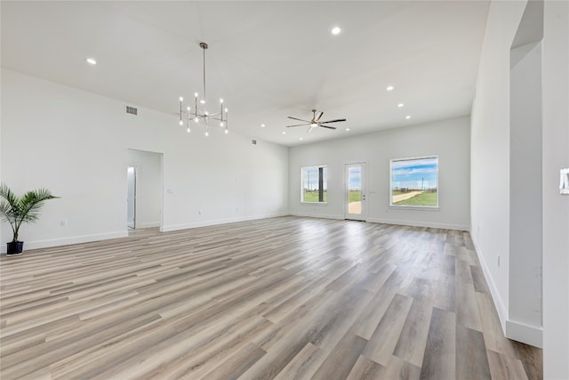 unfurnished living room with ceiling fan with notable chandelier and light hardwood / wood-style floors