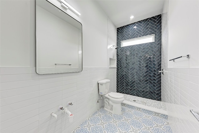 bathroom with tiled shower, tile patterned flooring, tile walls, and toilet