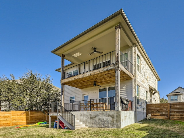 rear view of house with ceiling fan, a balcony, and a yard