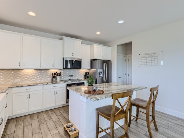 kitchen featuring white cabinets, stainless steel appliances, and light stone countertops