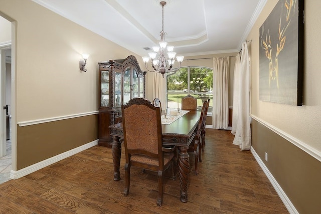 dining area with dark wood-type flooring, ornamental molding, a chandelier, and a tray ceiling