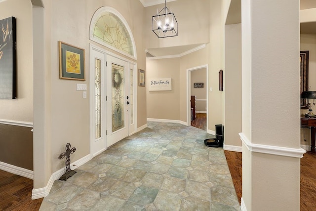 entryway with ornamental molding, light tile floors, and an inviting chandelier