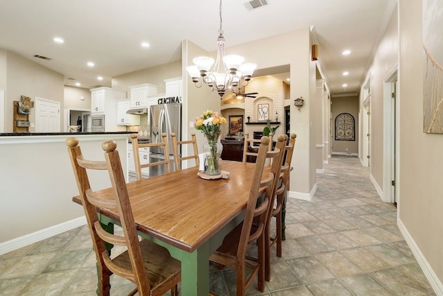 tiled dining area featuring a notable chandelier and a brick fireplace