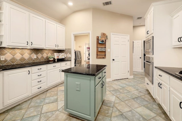 kitchen with white cabinets, stainless steel appliances, a center island, and light tile floors