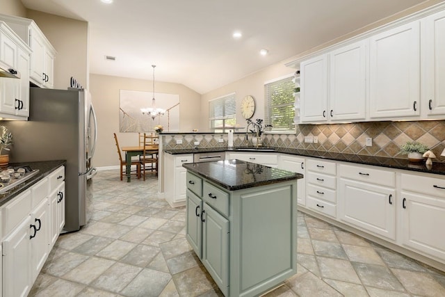 kitchen featuring pendant lighting, tasteful backsplash, a center island, a notable chandelier, and white cabinets