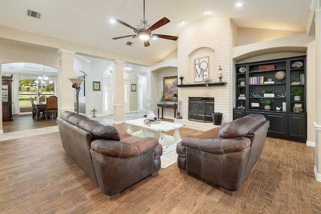 living room with ornate columns, lofted ceiling, a brick fireplace, and wood-type flooring