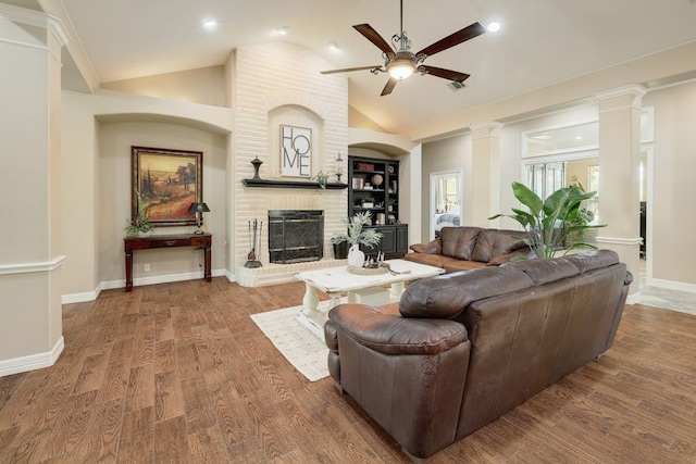 living room with ceiling fan, lofted ceiling, dark hardwood / wood-style floors, and a brick fireplace