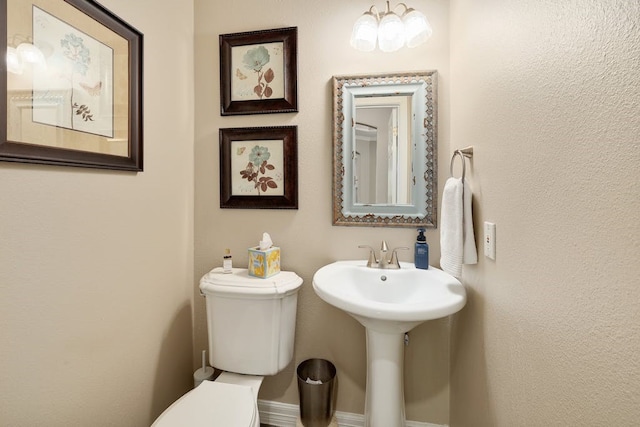 bathroom featuring a notable chandelier and toilet