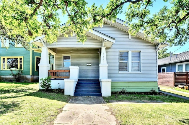 bungalow-style house featuring covered porch and a front lawn