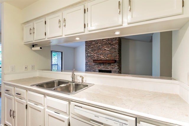 kitchen featuring white cabinets, dishwasher, a brick fireplace, and sink