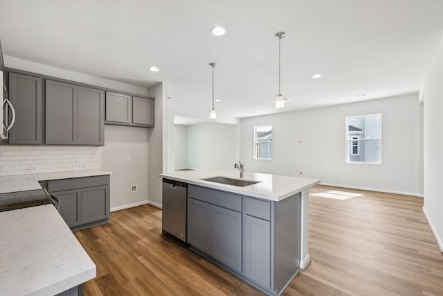 kitchen featuring sink, stainless steel dishwasher, pendant lighting, gray cabinets, and a center island with sink