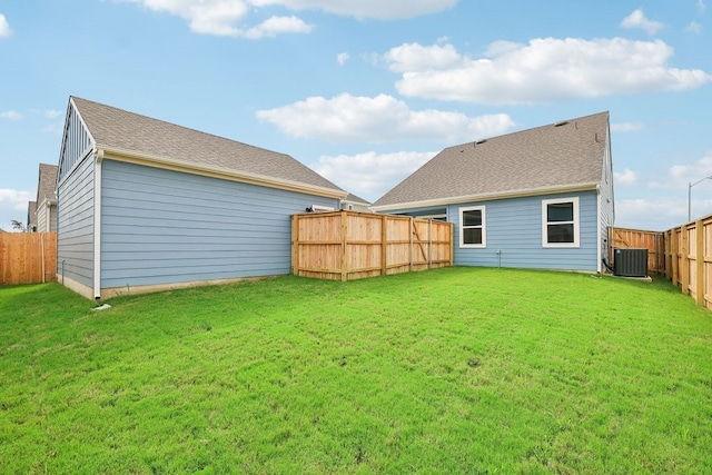 rear view of property with cooling unit and a lawn