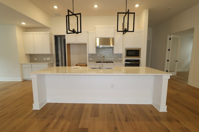 kitchen with white cabinetry, built in microwave, a large island, oven, and pendant lighting