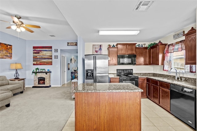 kitchen featuring a stone fireplace, light colored carpet, a center island, black appliances, and sink