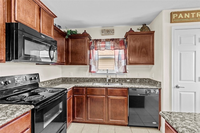 kitchen with light tile patterned floors, sink, black appliances, and light stone counters