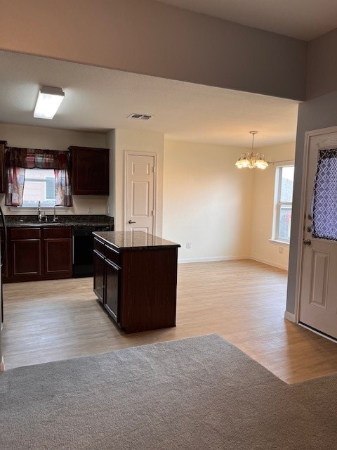 kitchen with light hardwood / wood-style floors, an inviting chandelier, dark brown cabinets, a kitchen island, and pendant lighting