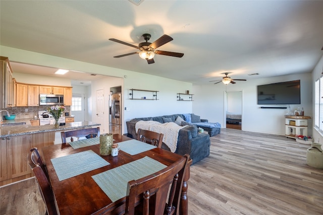 dining area with ceiling fan, sink, a healthy amount of sunlight, and light wood-type flooring