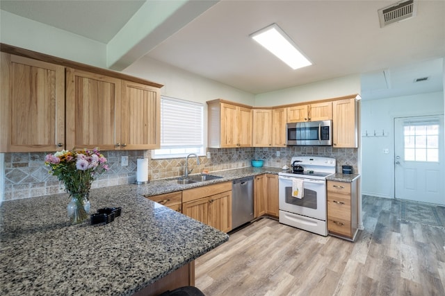 kitchen featuring appliances with stainless steel finishes, light hardwood / wood-style flooring, plenty of natural light, and sink