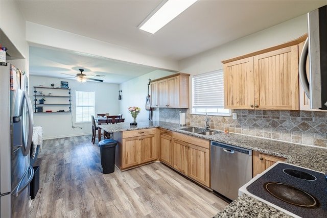 kitchen with kitchen peninsula, light wood-type flooring, stainless steel appliances, sink, and light brown cabinets