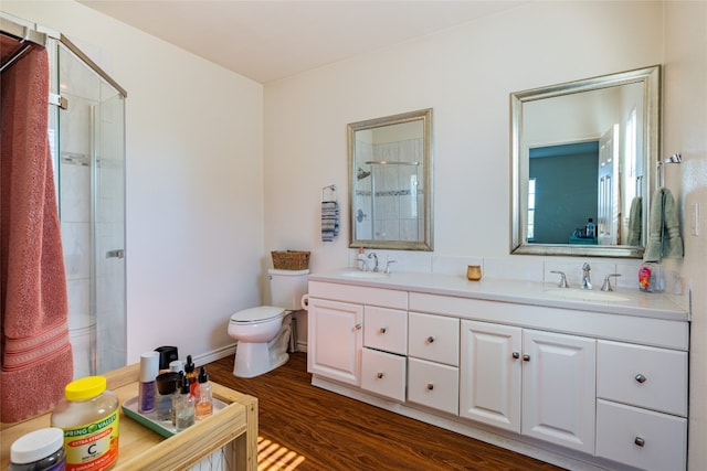 bathroom featuring wood-type flooring, vanity, toilet, and a shower with shower door