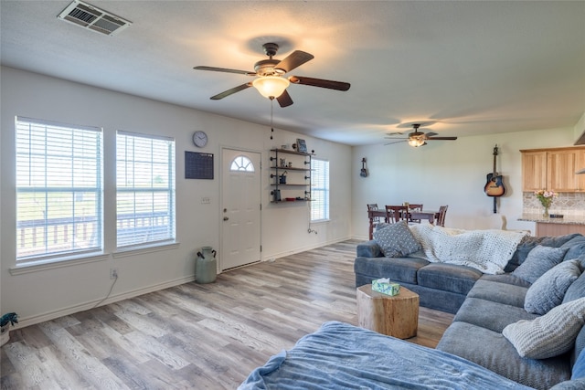 living room featuring light hardwood / wood-style floors, ceiling fan, and a healthy amount of sunlight