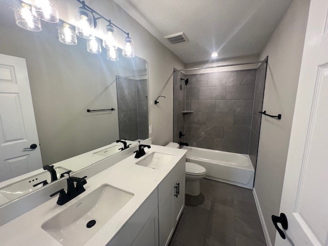 full bathroom with tile patterned floors, tiled shower / bath, toilet, and vanity