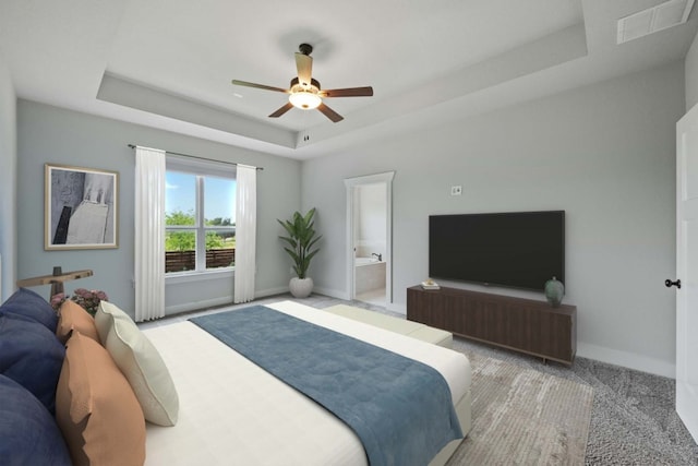 carpeted bedroom with ceiling fan, ensuite bath, and a tray ceiling