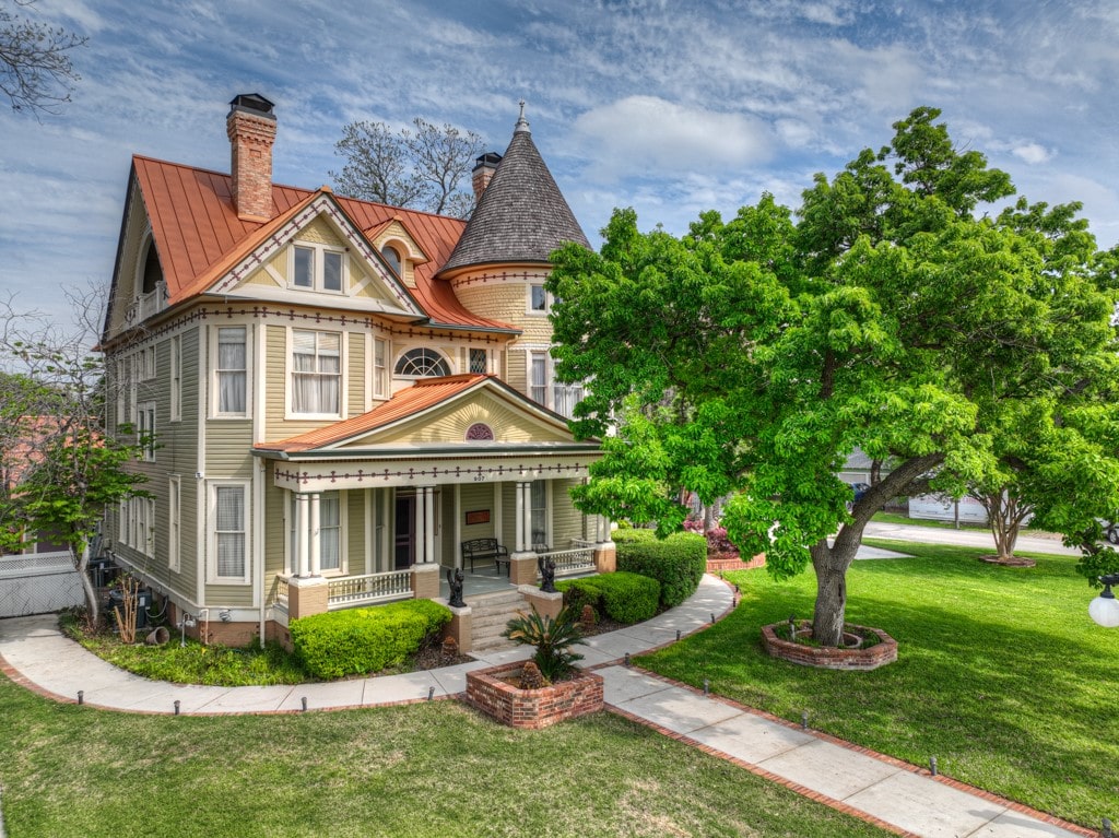 victorian house with covered porch and a front lawn