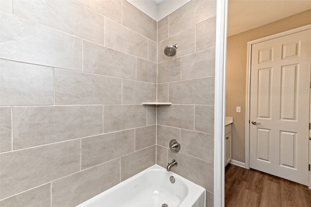 bathroom featuring wood-type flooring, tiled shower / bath, and vanity