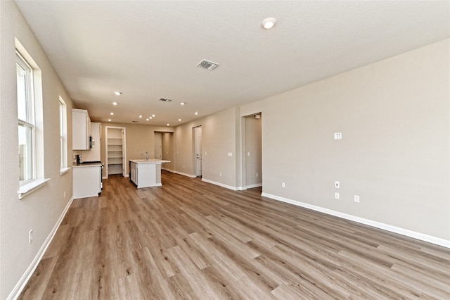 unfurnished living room featuring light wood-type flooring and sink