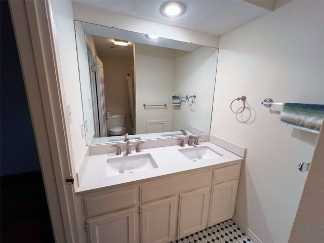 bathroom with vanity, a textured ceiling, and toilet