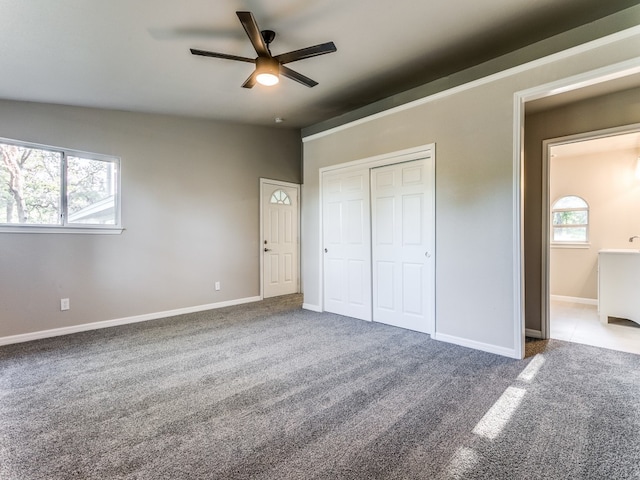 unfurnished bedroom featuring multiple windows, light carpet, ceiling fan, and a closet