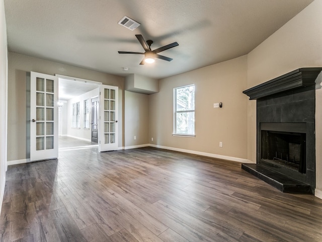 unfurnished living room with a textured ceiling, french doors, ceiling fan, and dark wood-type flooring